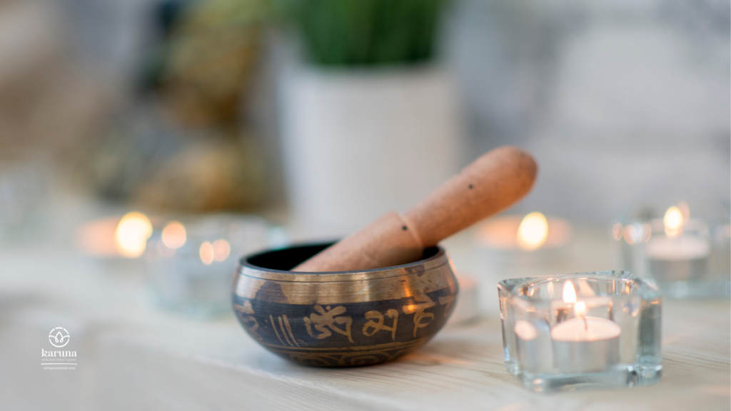 A traditional singing bowl and mallet with candles sitting around the bowl.