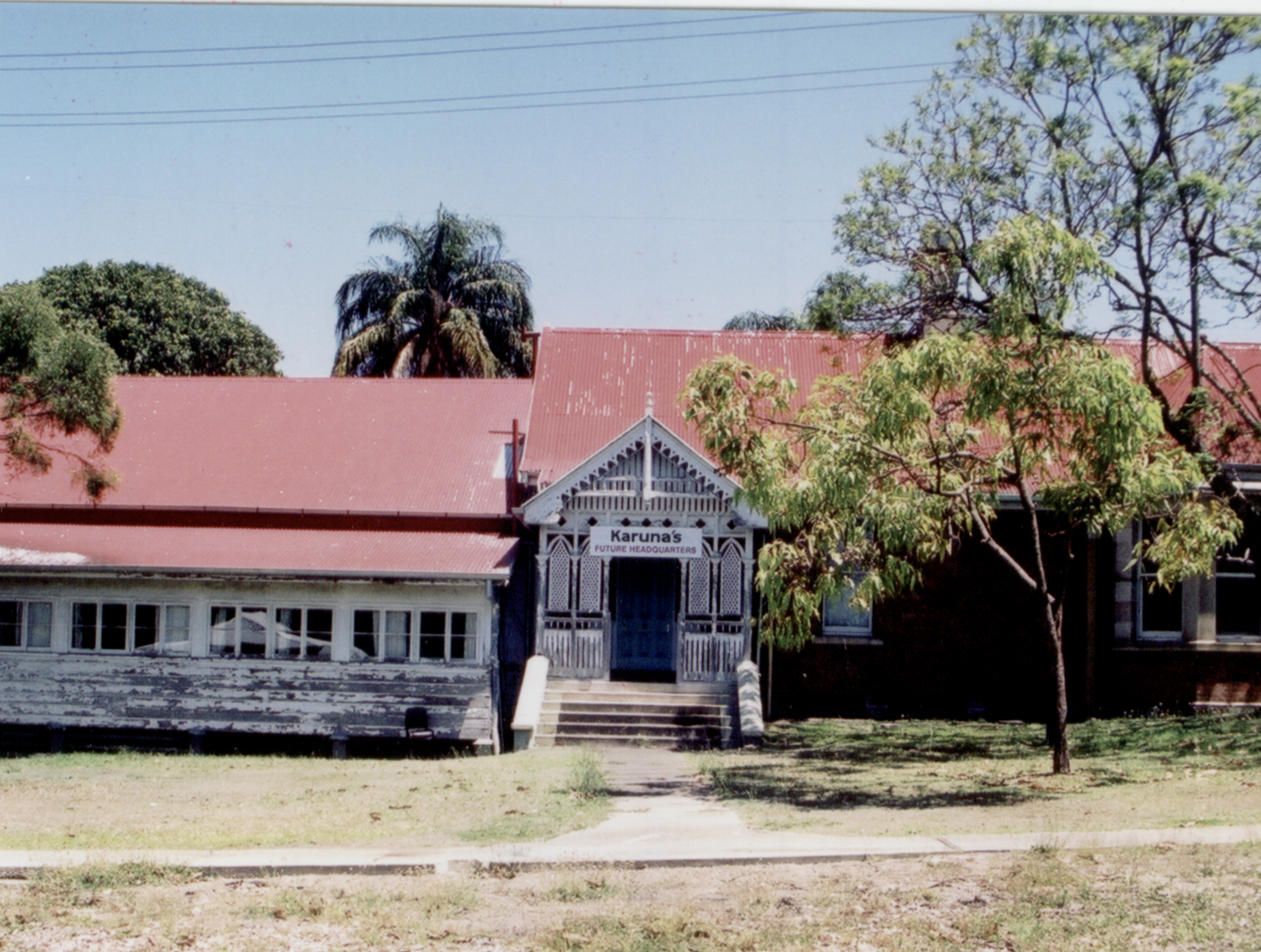 A building with a red roof and white wooden accents, featuring a sign that reads "Karuna's Headquarters."